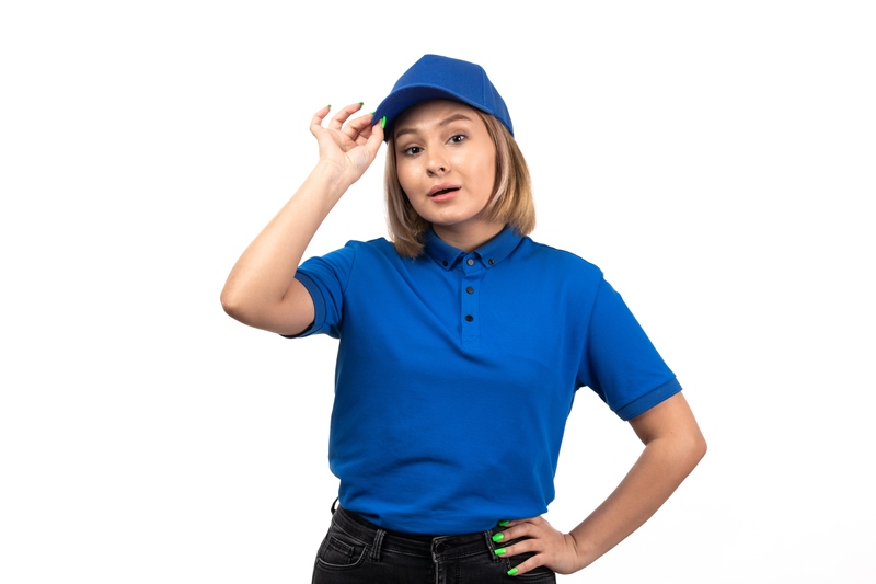 a front view young female courier in blue uniform just posing on the white background service job delivering