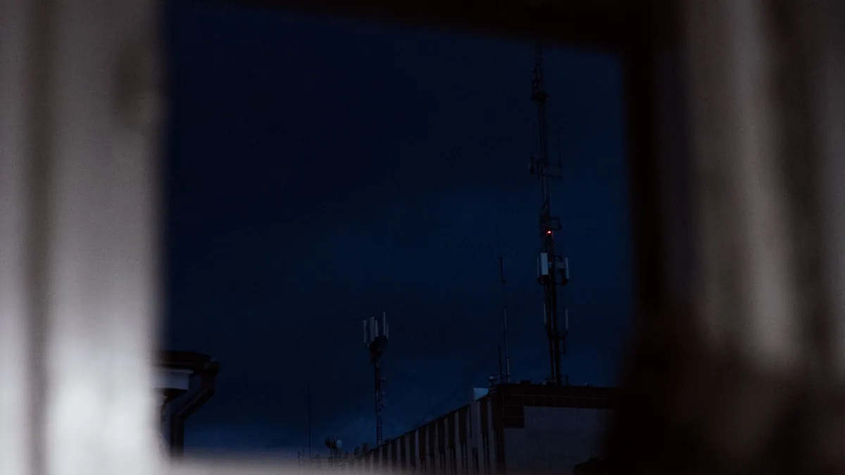 Antene de telecomunicații văzute noaptea printr-o fereastră